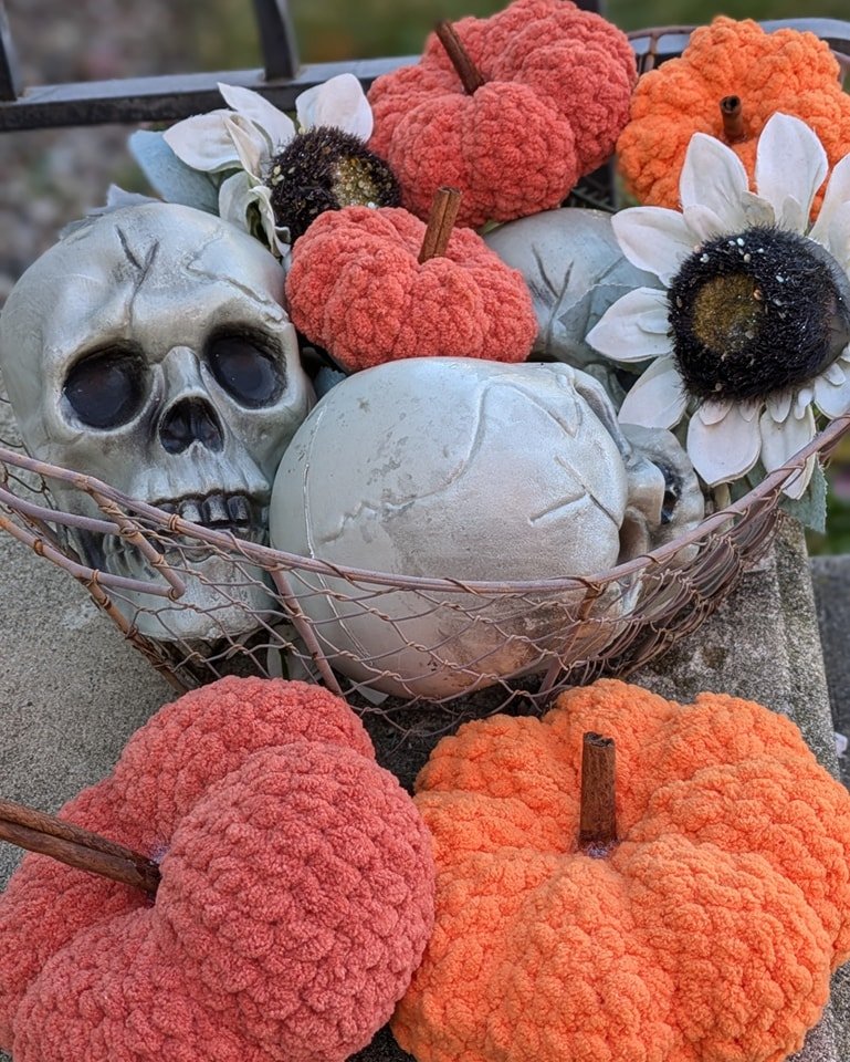 Handmade crocheted pumpkins displayed with decorative skulls